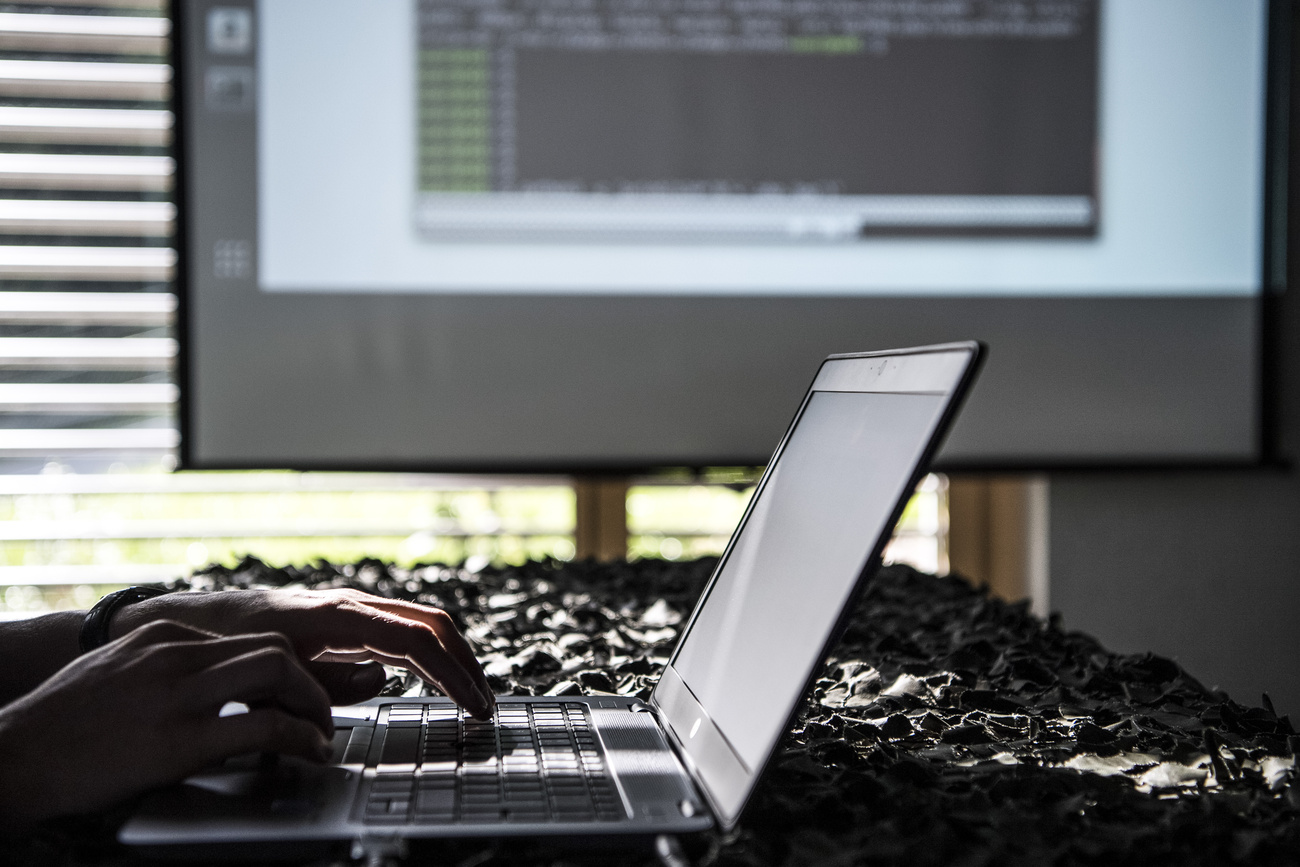 Person typing on a laptop with code projected on a screen in the background