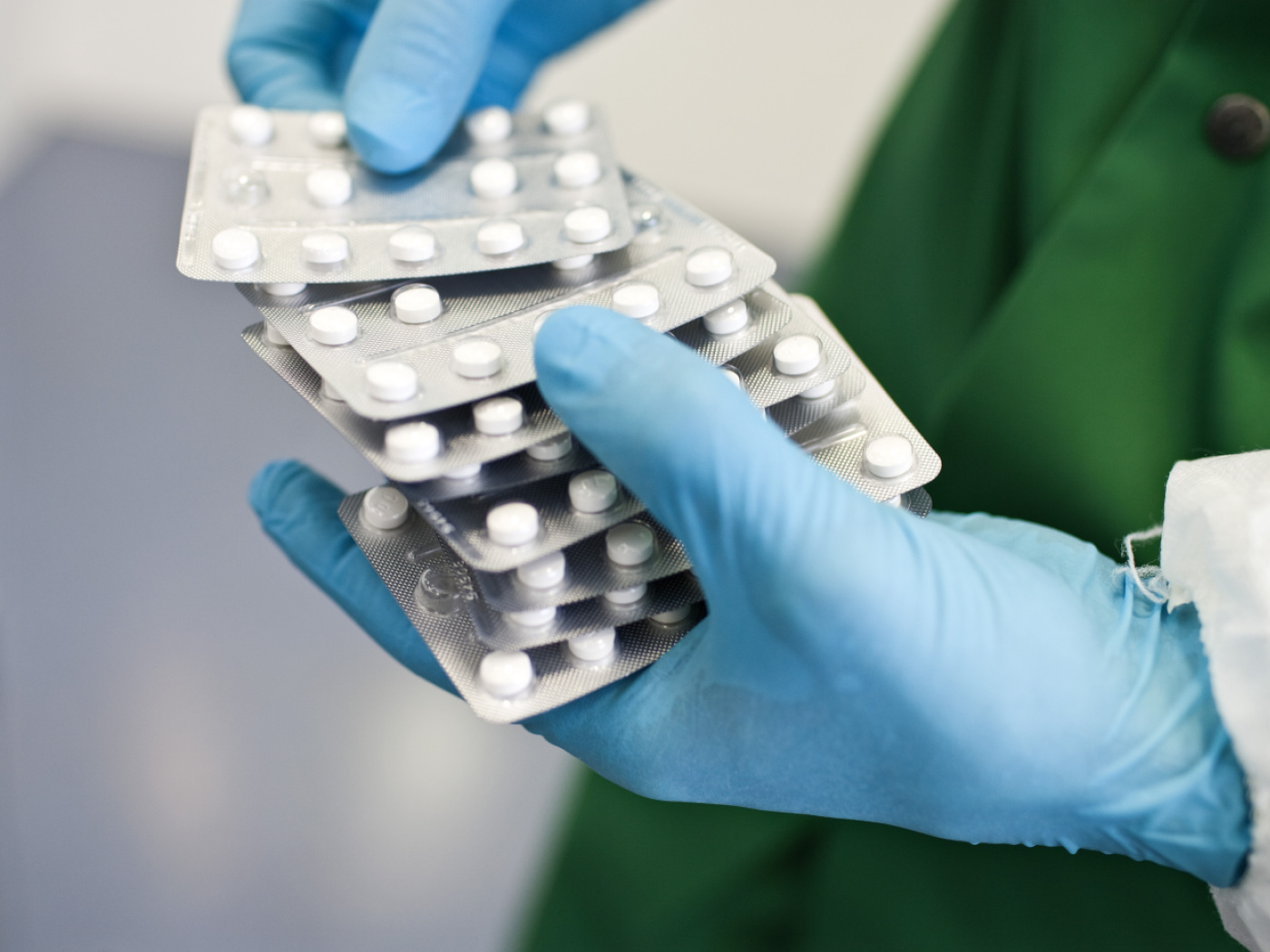 persona con guanti fi latex azzurri maneggia blister di pastiglie