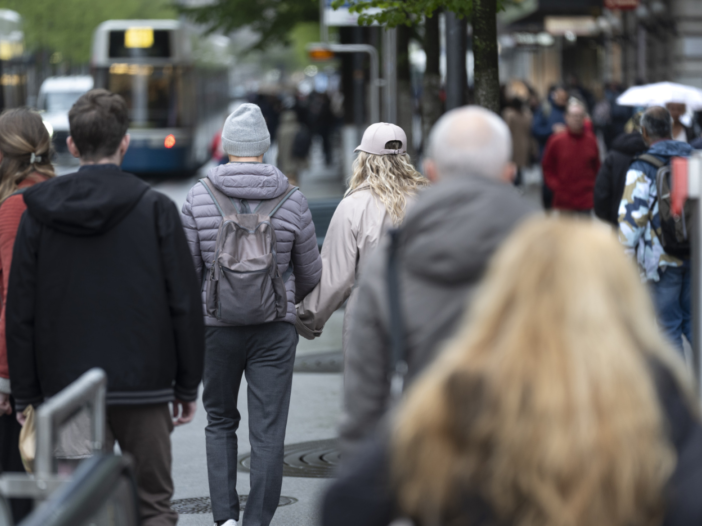 coppia mano nella mano fotografata di spalle nella folla