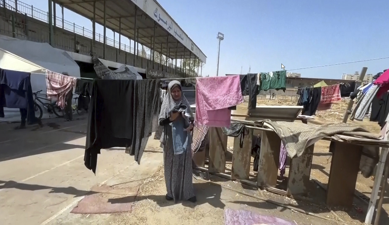 A displaced woman hanging laundry at Yarmouk stadium in Gaza City, now a shelter.