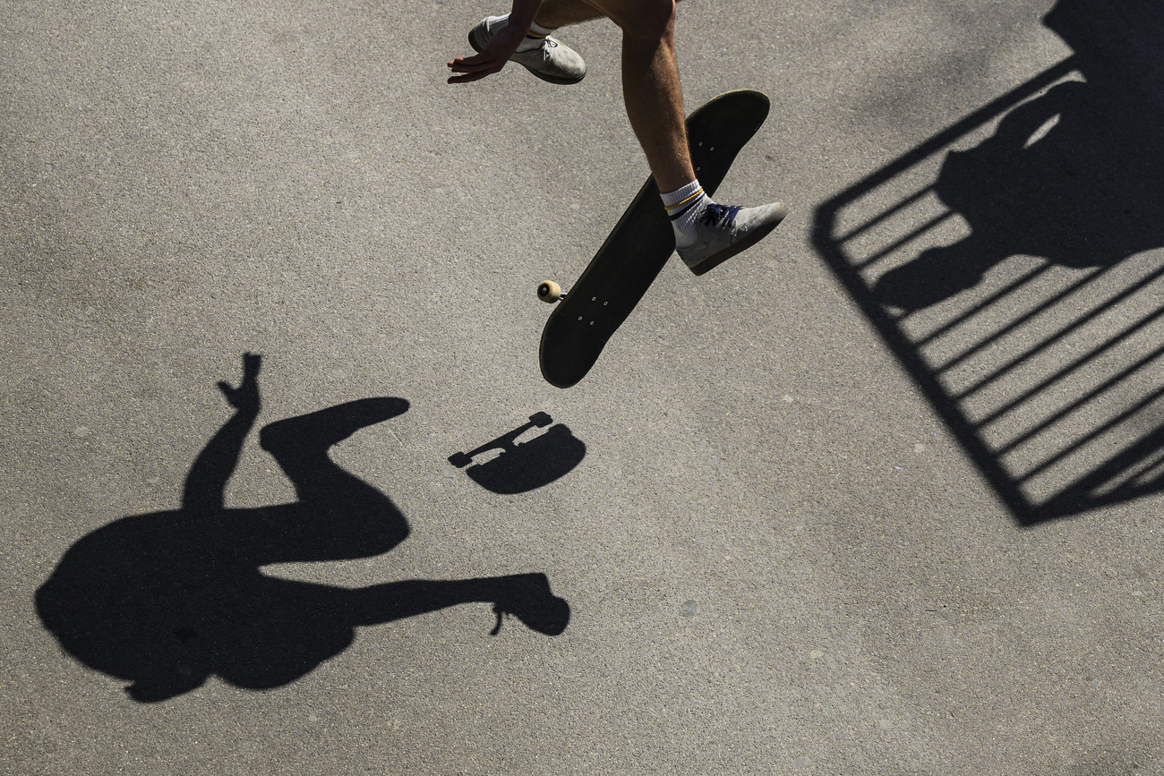 skater effettua un salto, visibili le gambe, lo skateboard e l'ombra