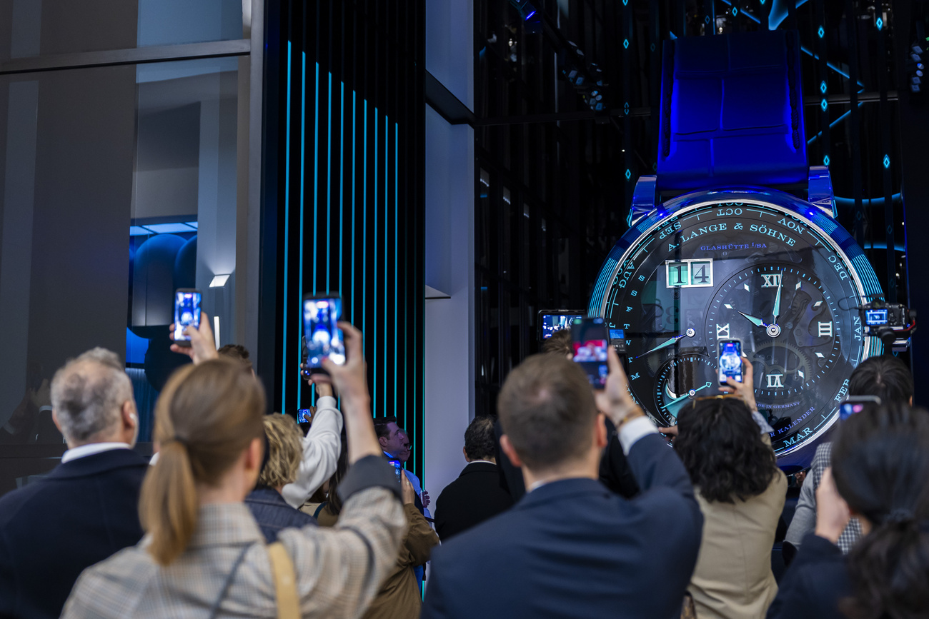Visitatori e visitatrici del salone dell'orologeria Watches and Wonders fotografano un orologio gigante del produttore tedesco A. Lange & Söhne.