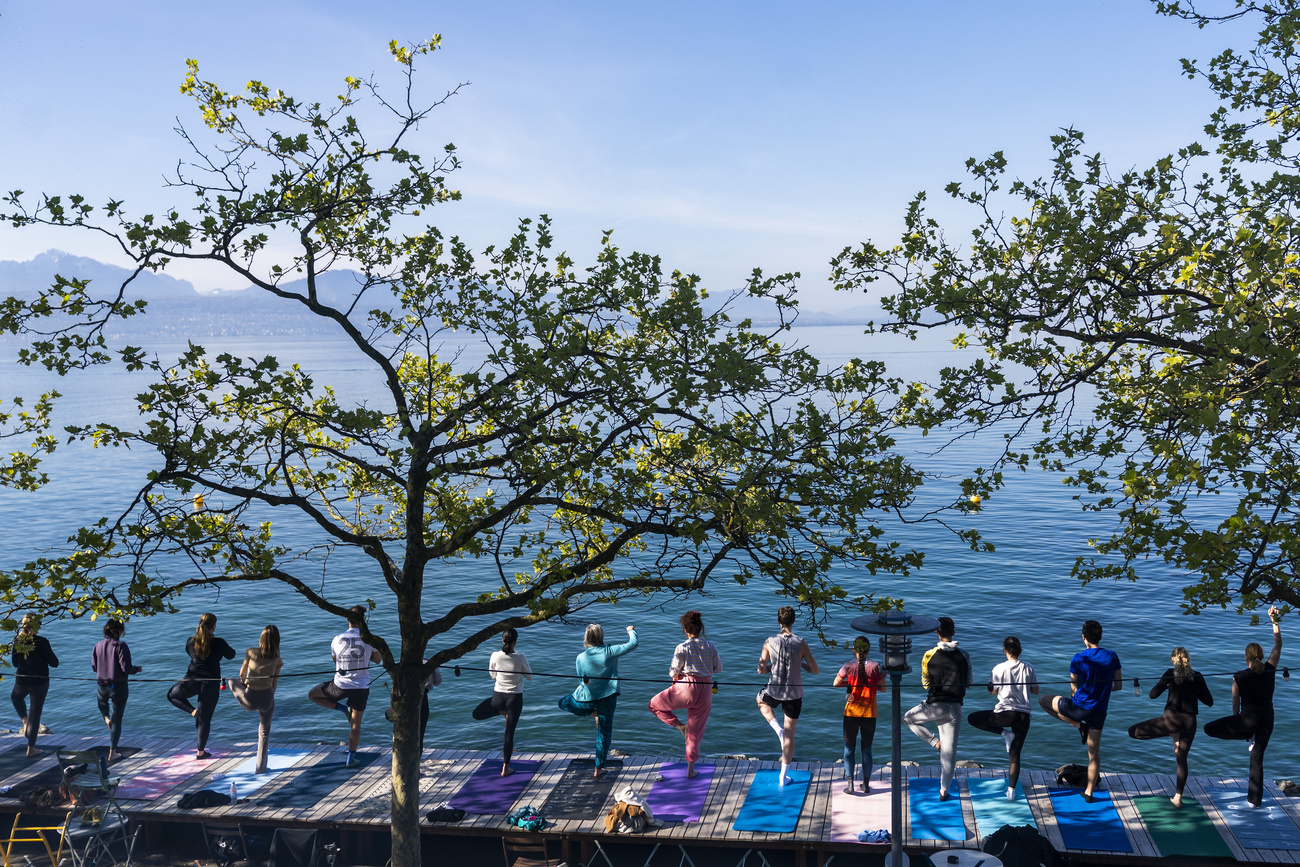 Persone praticano lo yoga sul bordo di un lago