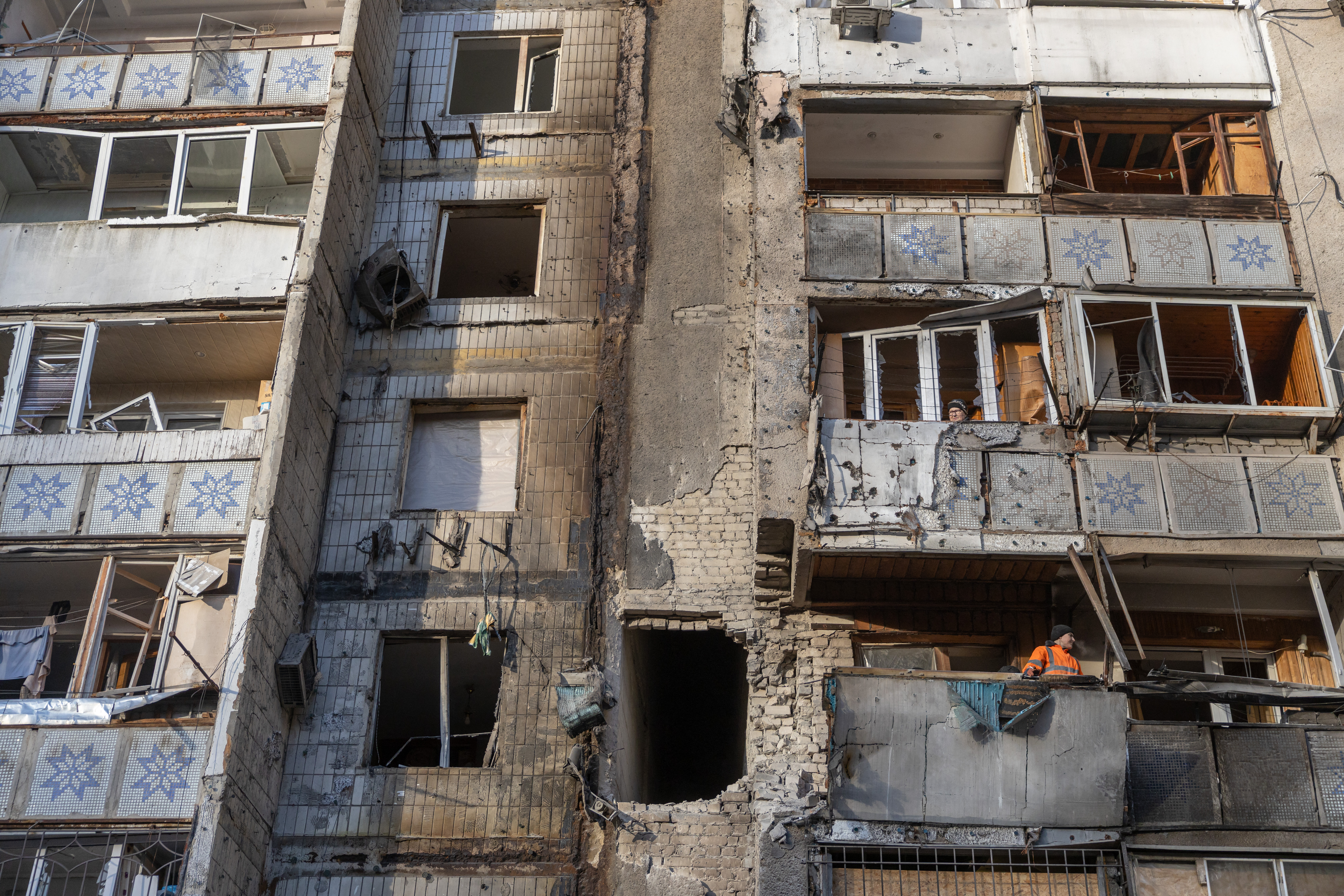 The damaged façade of a multi-storey building, with broken windows and exposed interiors