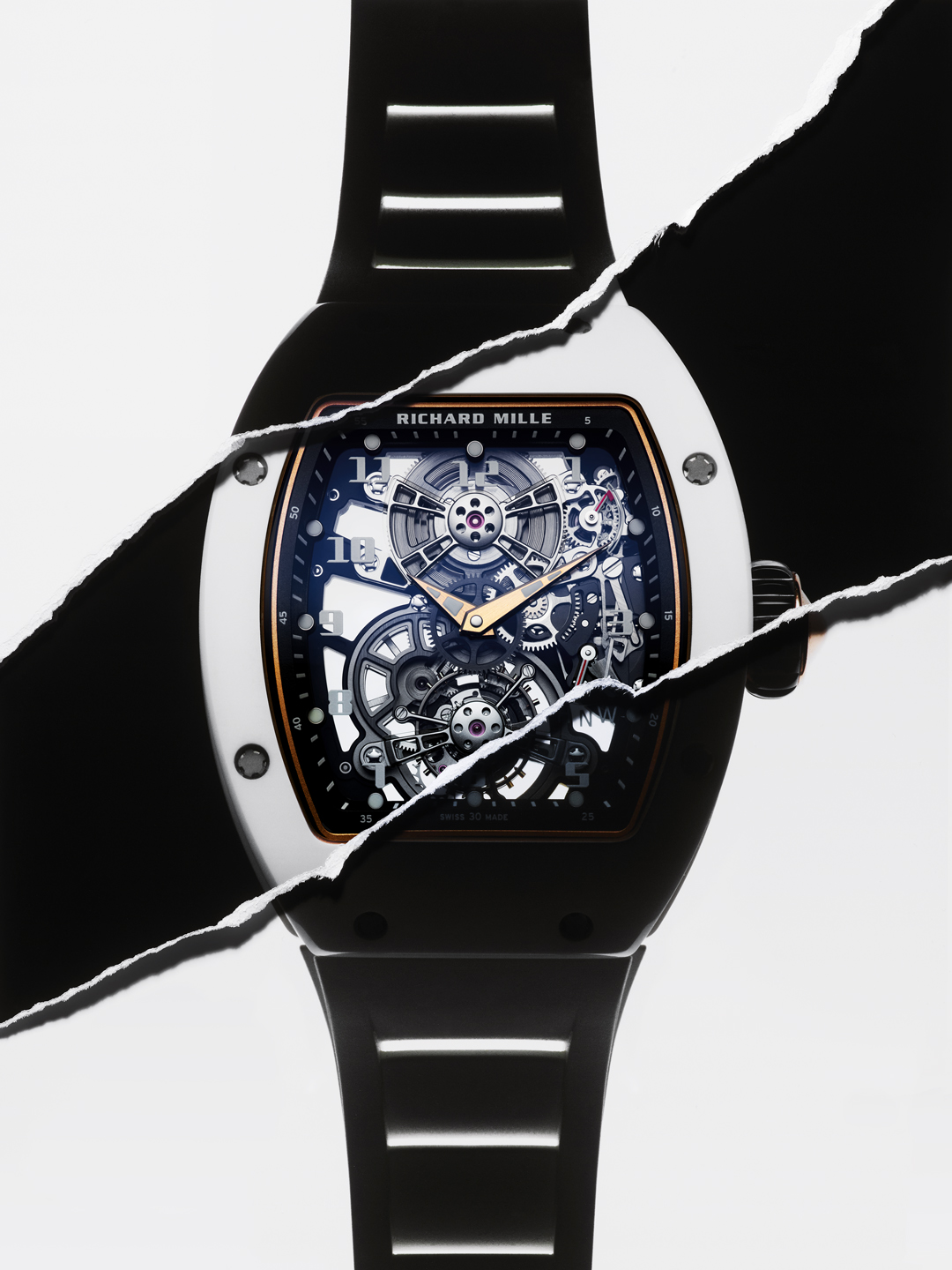 Gros plan du cadran d'une montre Richard Mille dont les rouages sont visibles, derrière des couches de papier noir et blanc déchirées.