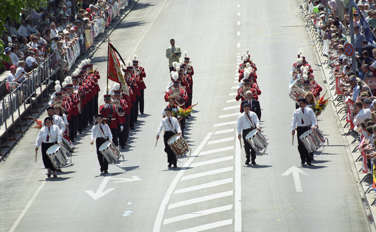 Blasmusik-Formation bei einer Parade auf einer von Zuschauern gesäumten Strasse
