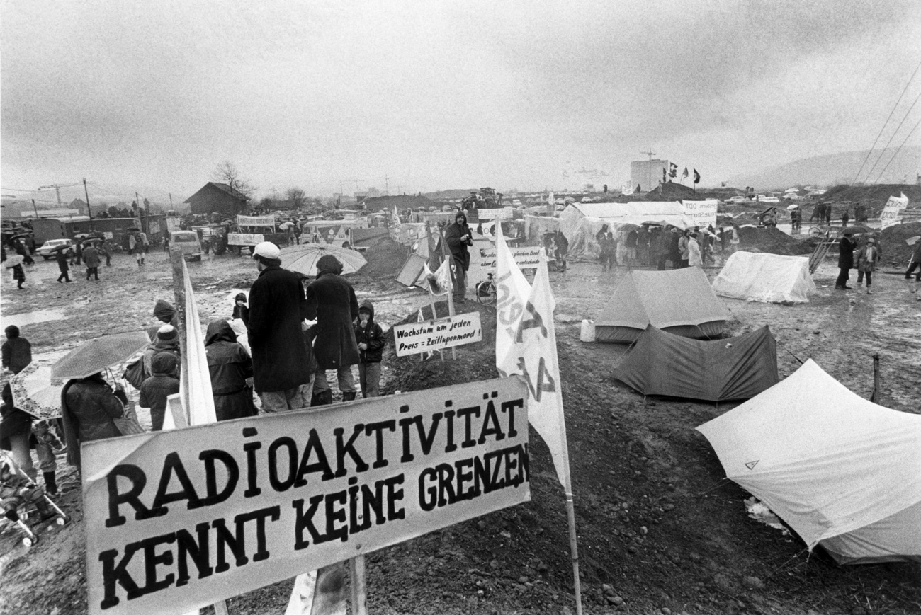 Черно-белая фотография запыленного лагеря протестующих с палатками и плакатами
