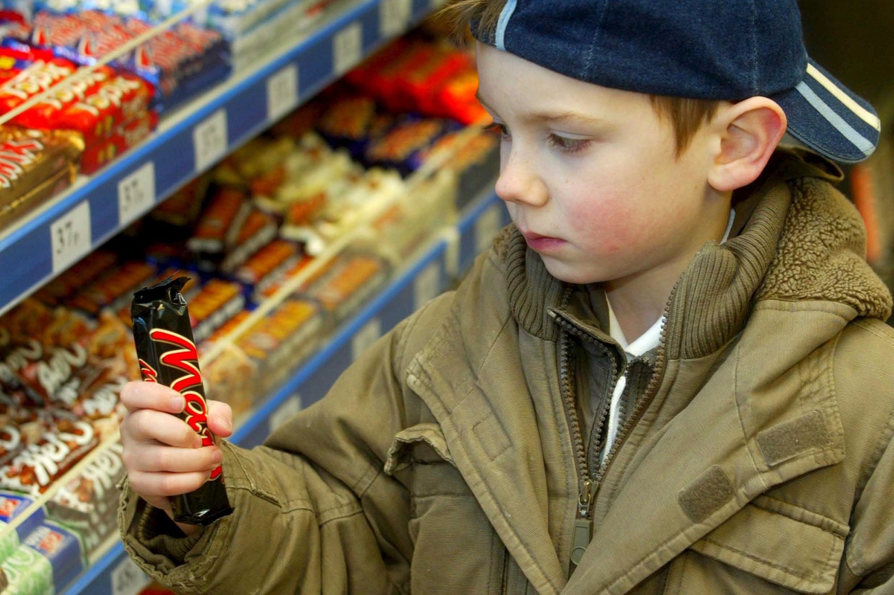 bambino con barretta mars in mano al supermercato