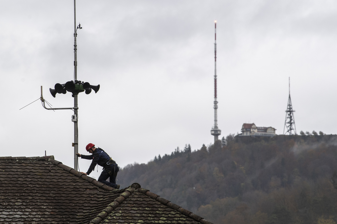Workers in protective clothing inspecting the siren system on the roof
