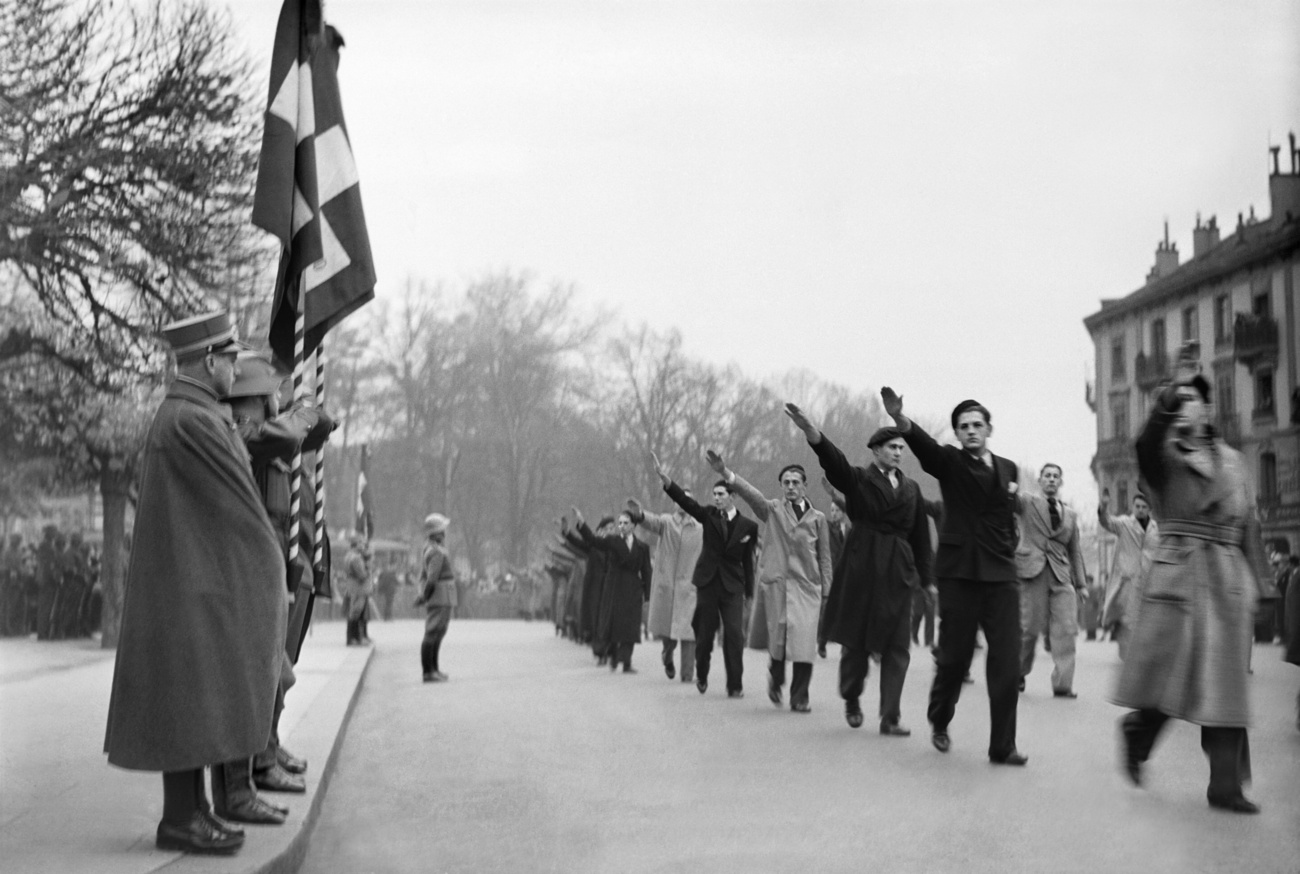 Parte de uma vasta rede de apoio germanófila: grupo de nazistas suíços marcha fazendo a saudação nazista a um oficial do exército suíço em Genebra, 1938.