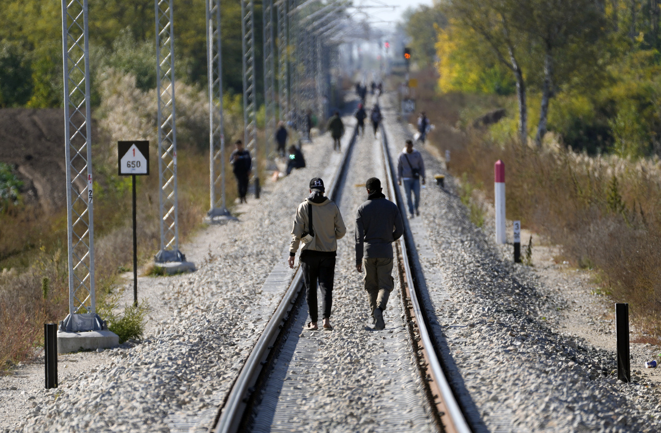 migranti camminano su binari