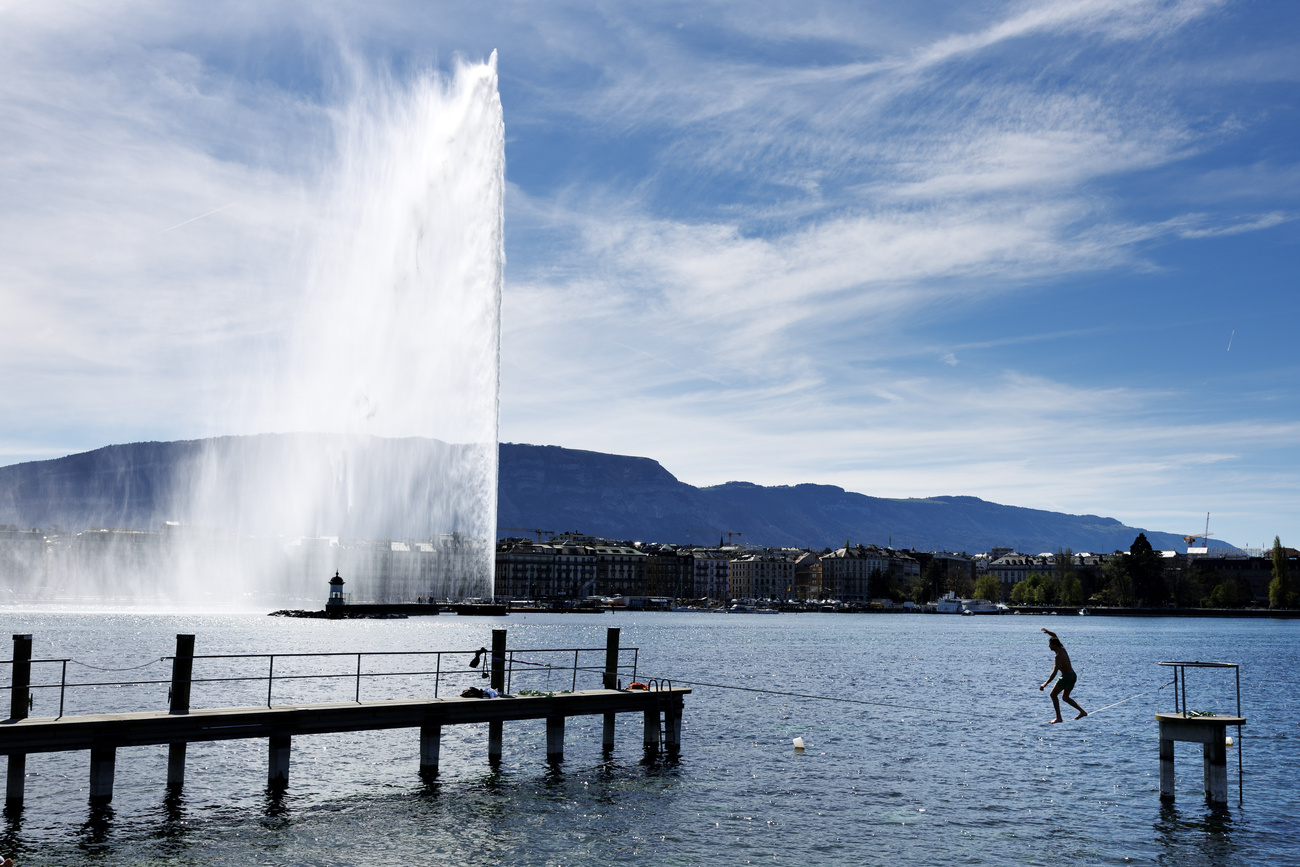 A person walking on a slackline in front of the Jet d'Eau