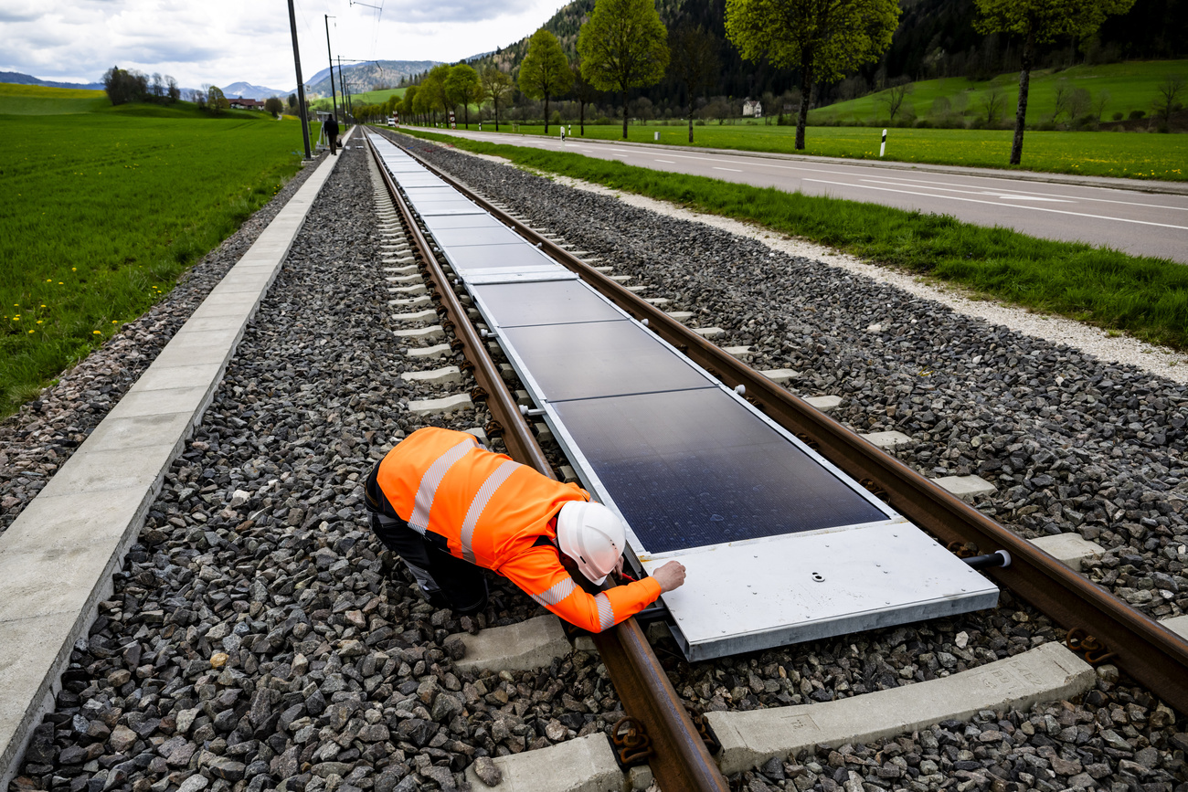 A railway worker inspects the solar panels installed between the tracks