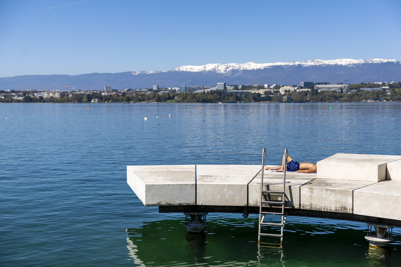 Un uomo prende il sole su una piattaforma balneare sulle rive del Lago Lemano a Ginevra.