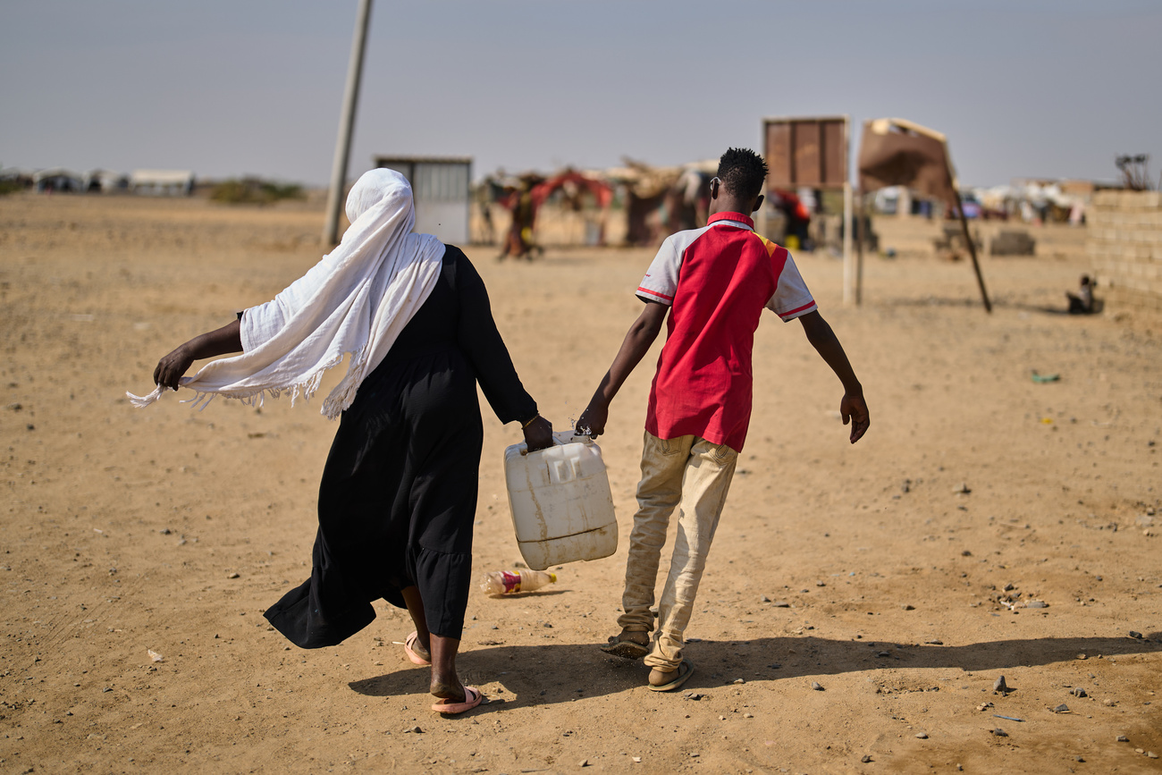 Des Soudanais déplacés à l'intérieur du pays transportent de l'eau dans le camp d'Al Heshan, aux abords de Port-Soudan, le 15 avril 2026.