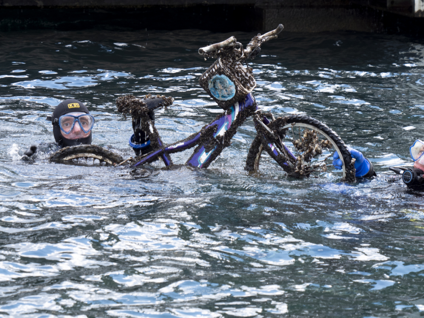 sommozzatori emergono dal lago con una bicicletta