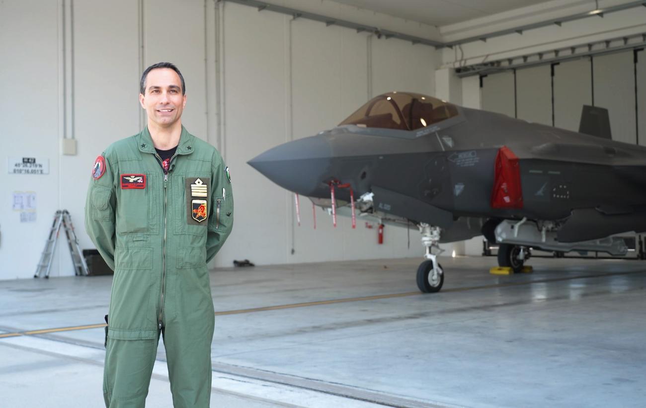 Un uomo in divisa militare, alle sue spalle un aereo da guerra.