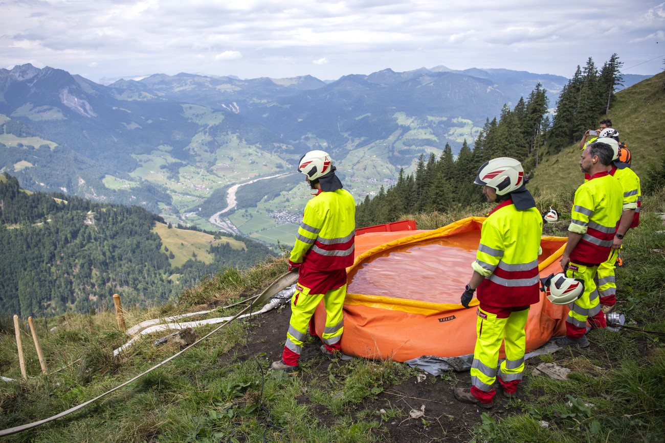 firefighters carrying a water bag in the mountains