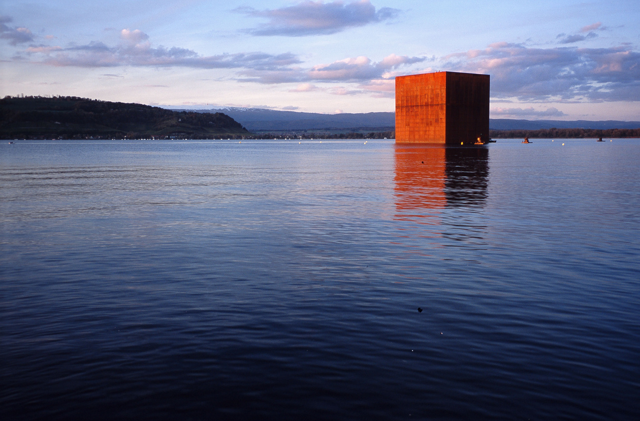 Ein riesiger Würfel aus rostigem Metall in einem See