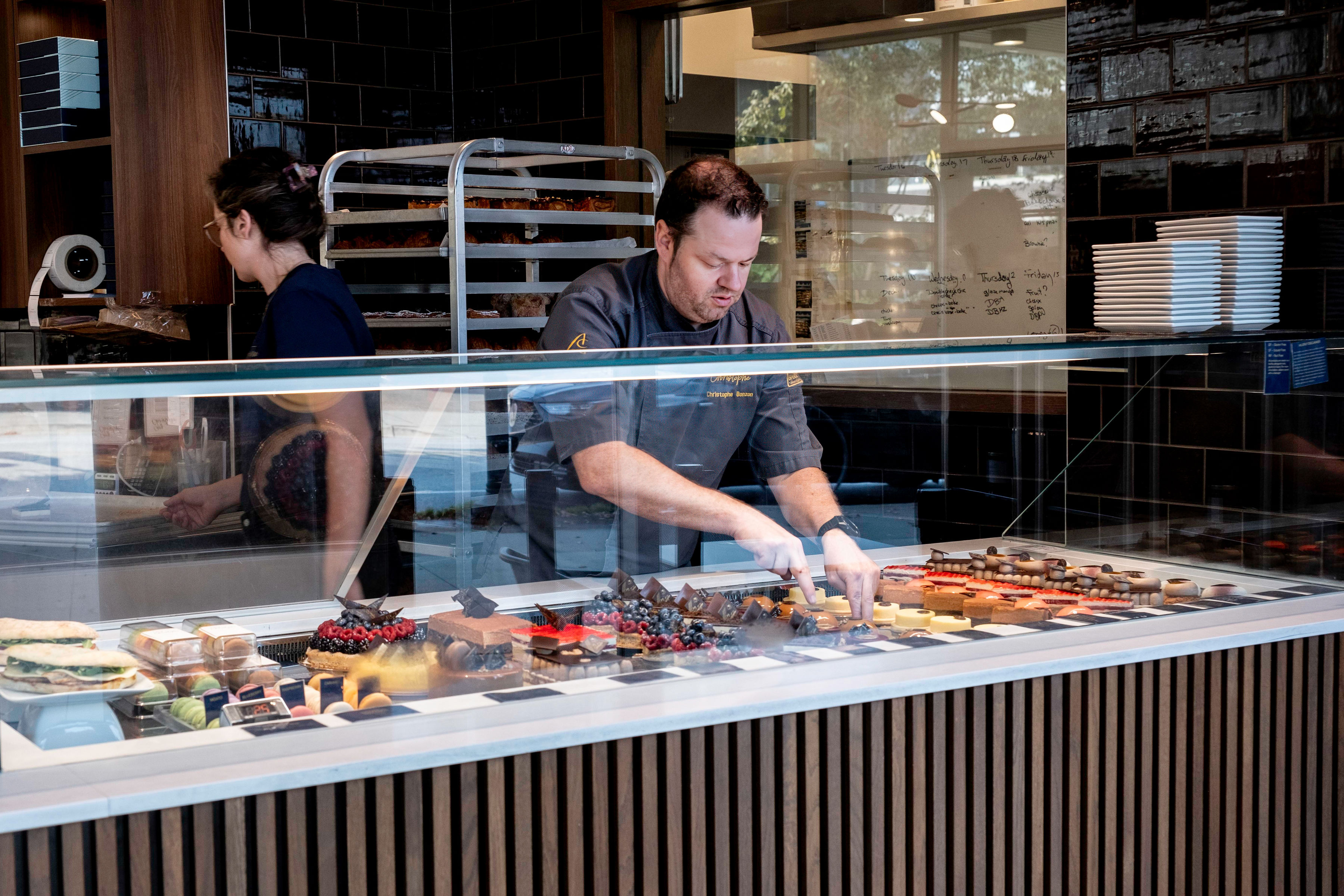 un homme installe des pâtisseries dans sa vitrine
