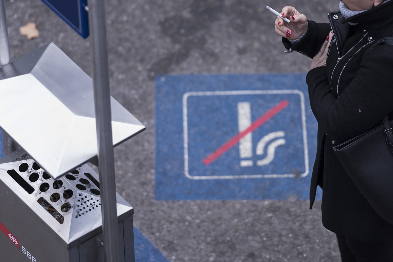 A female smoker smokes in a smoking ban area on a plattform at Stadelhofen train station in Zurich, Switzerland, on January 17, 2019. (KEYSTONE/Christian Beutler)