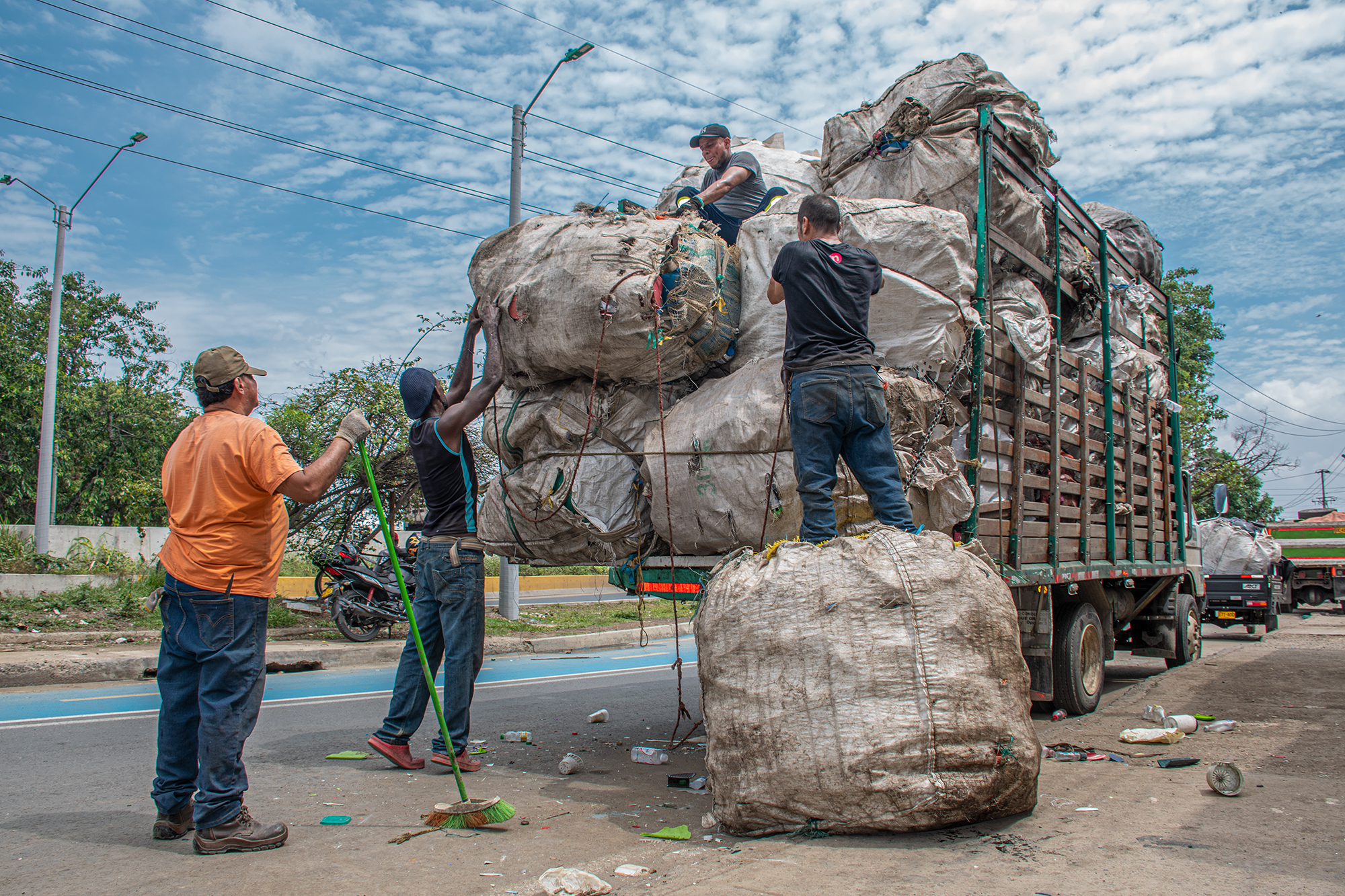 Rubbish workers in Cali, Colombia loading up bags of recyclable waste onto a truck.
