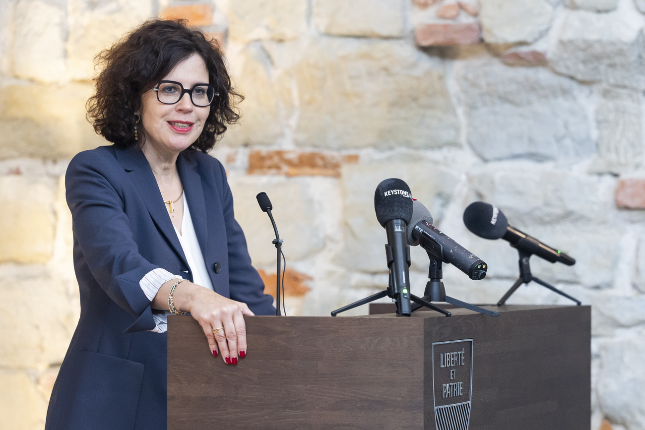 Eine Frau mit Brille an einem Rednerpult mit Mikrofonen