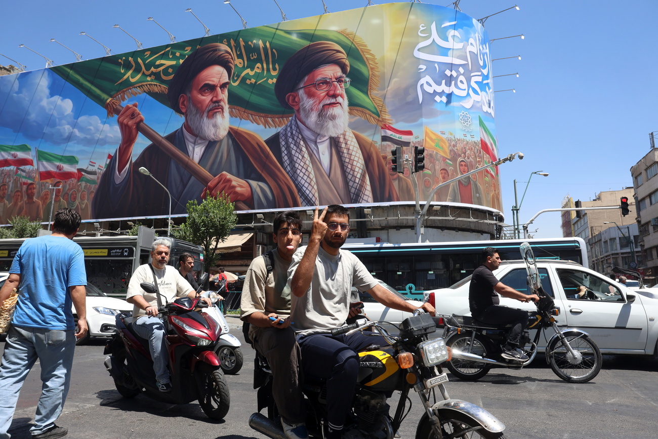 uomo in motorino a teheran mostra il segno della vittoria con le dita