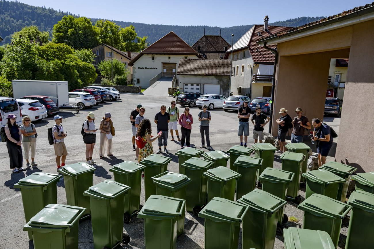Persone di fronte a molti bidoni dell'immondizia