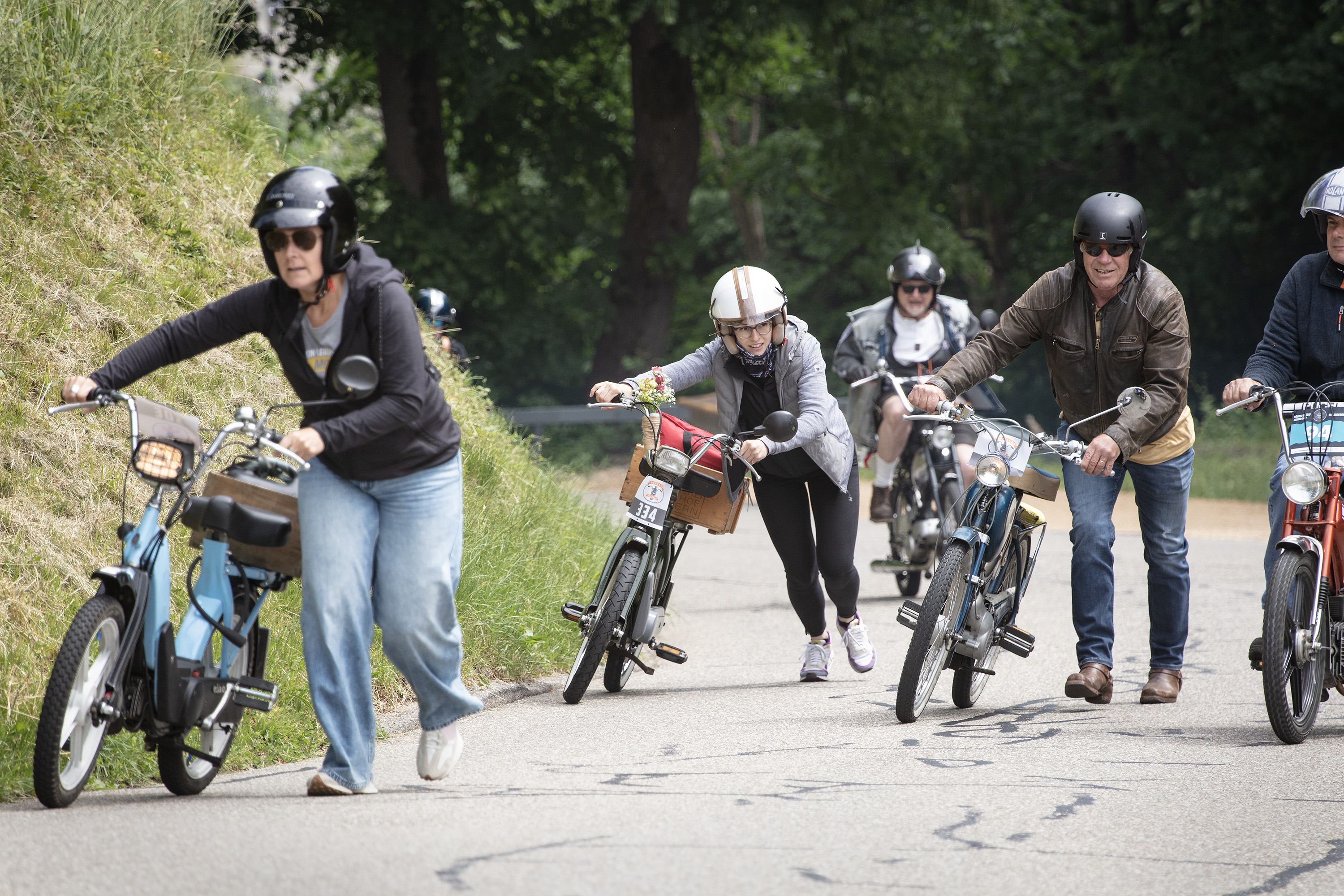 Leute schieben ihr Mofa eine steile Strasse hoch