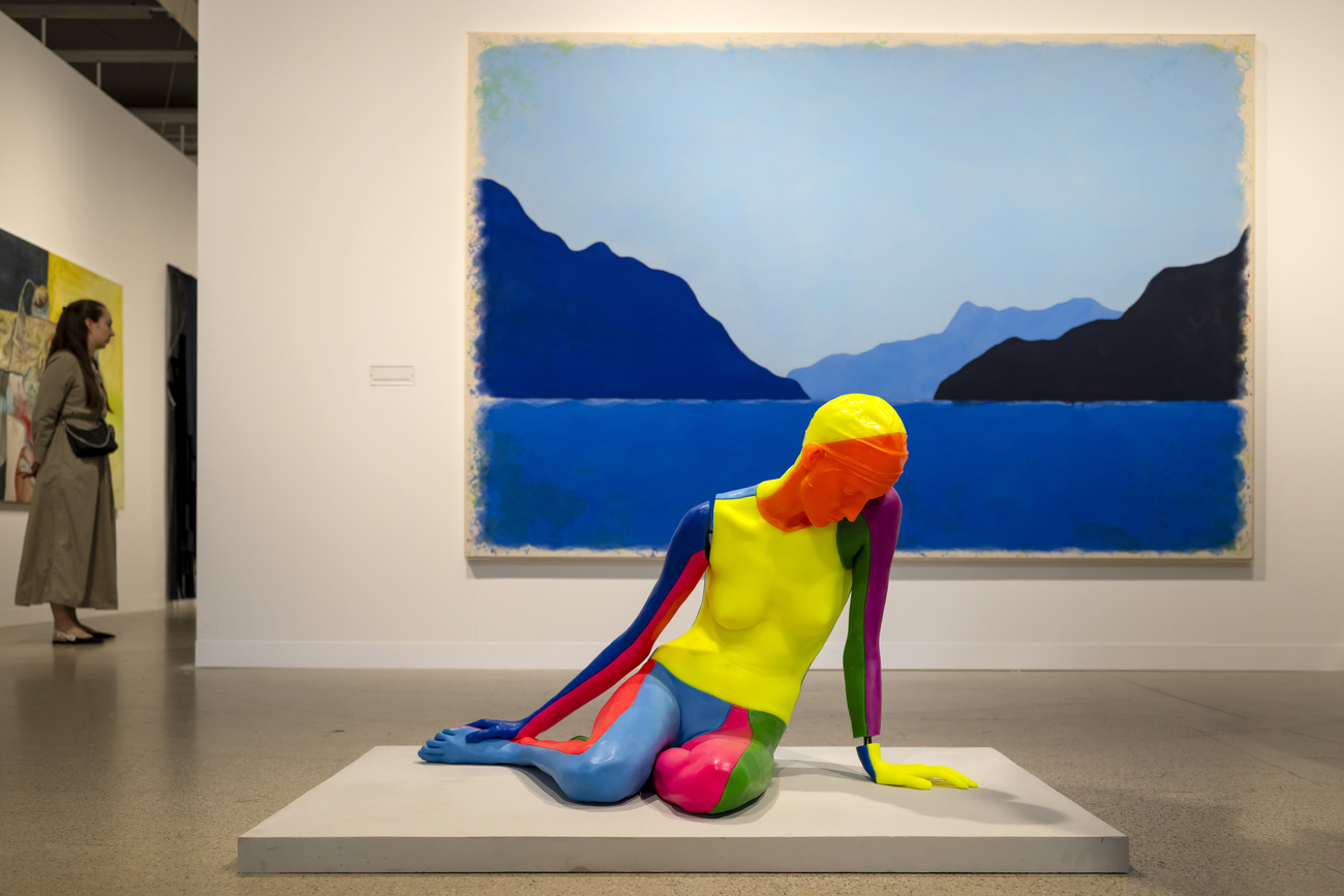 Работы NUDE (2021), на переднем плане, и ZWANZIGSTERMAIZWEITAUSENDSECHSUNDZWANZIG (2026), на заднем плане, швейцарского художника Уго Рондиноне (Ugo Rondinone) на международной художественной ярмарке Art Basel 2026 в Базеле, Швейцария, в среду, 17 июня 2026 года.