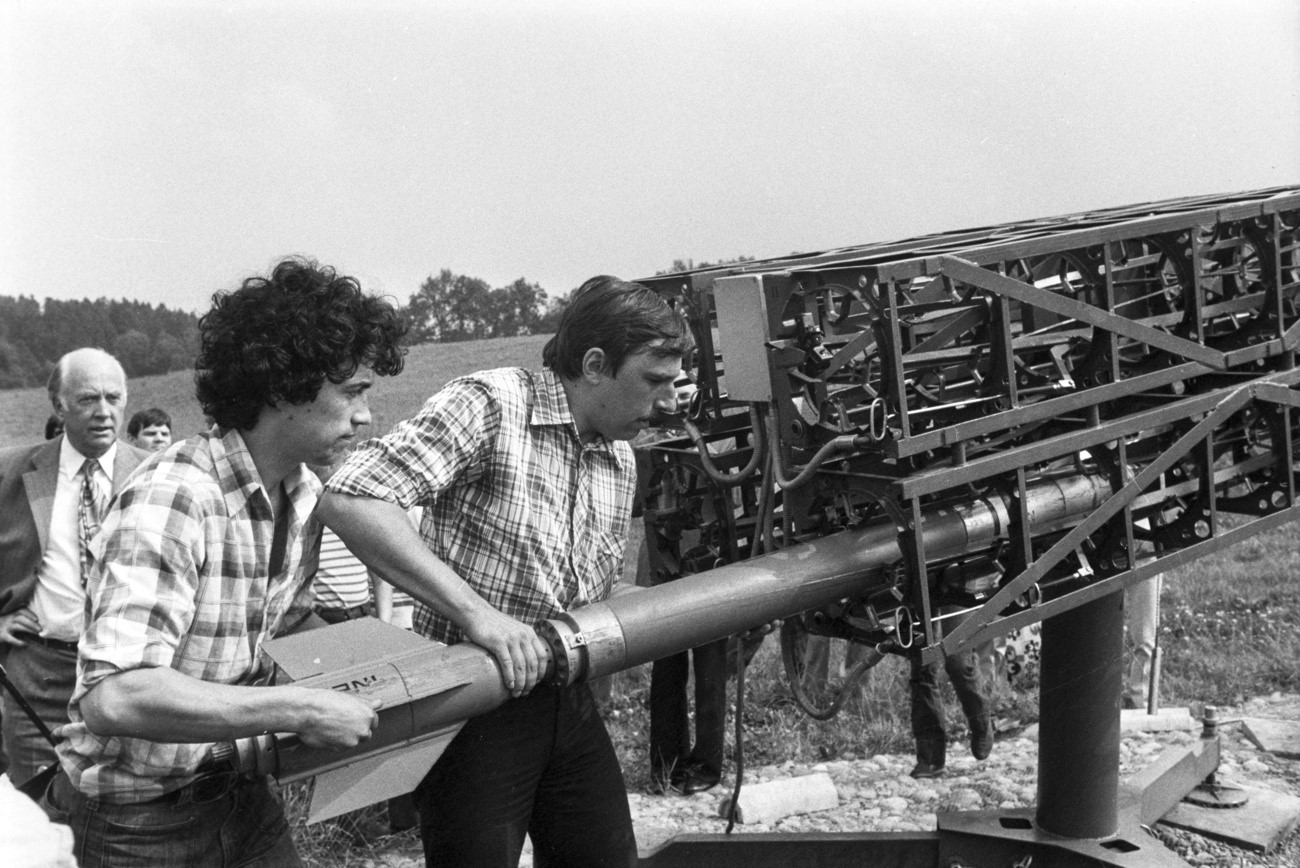 Two men are loading a rocket into a rocket launcher; black-and-white photograph