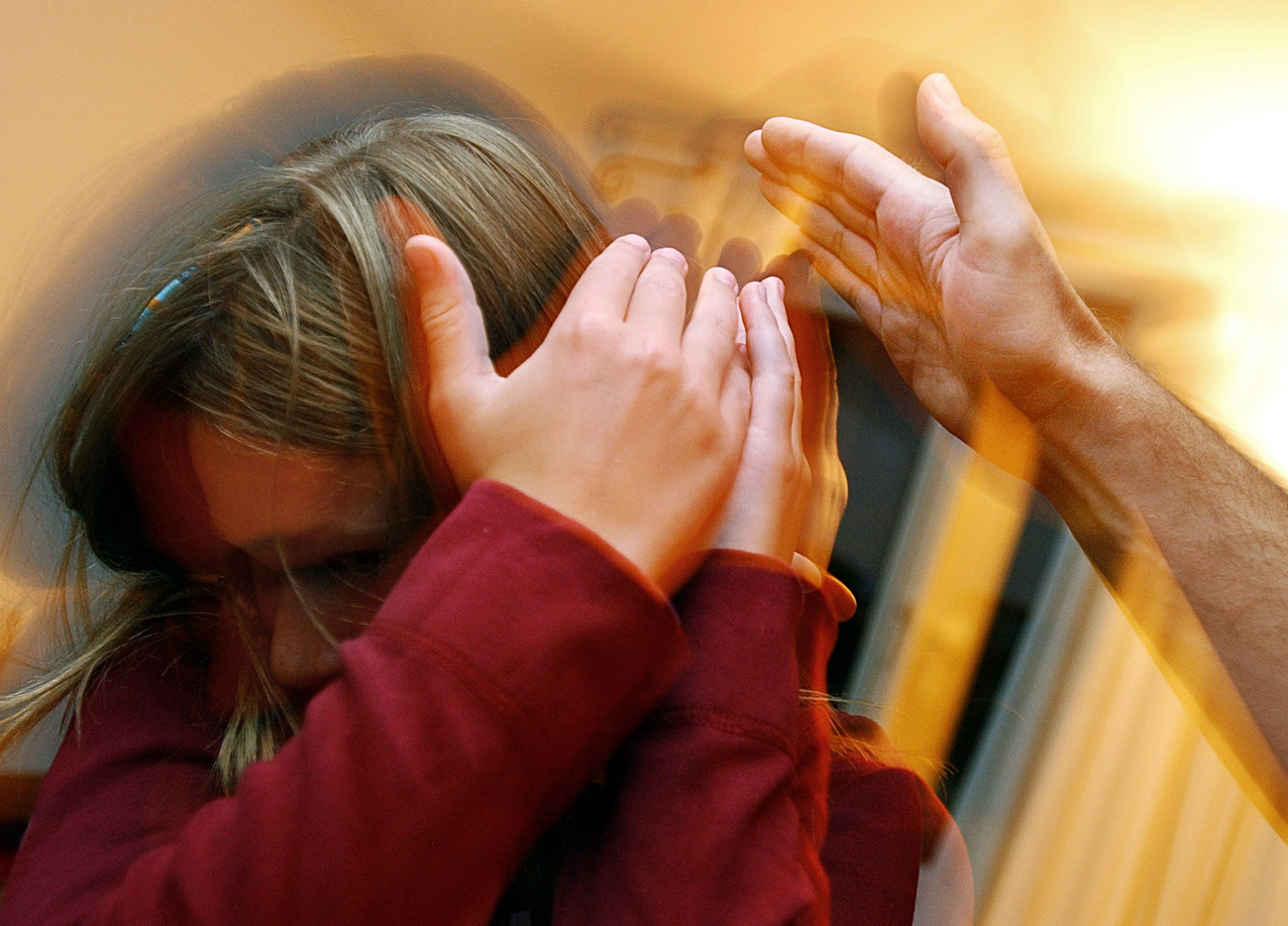 Bambina si protegge dalla mano di un adulto