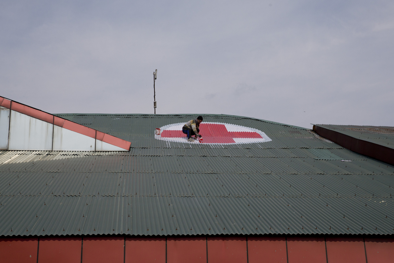 A Kashmiri worker paints the red and white medical emblem in the shape of a cross on the roof of the SMHS hospital as tensions escalate between India and Pakistan in Srinagar, in Indian-administered Kashmir, on Wednesday 27 February 2019. (AP Photo/Dar Yasin)