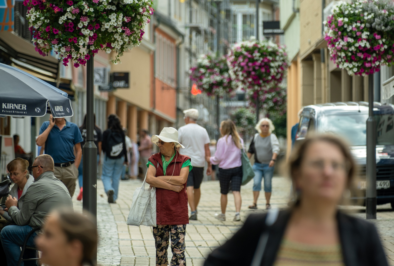 Une vieille dame au milieu d'une foule dans une rue commerçante piétonne