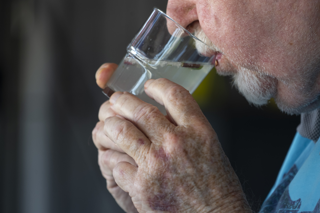 uomo anziano beve da un bicchiere