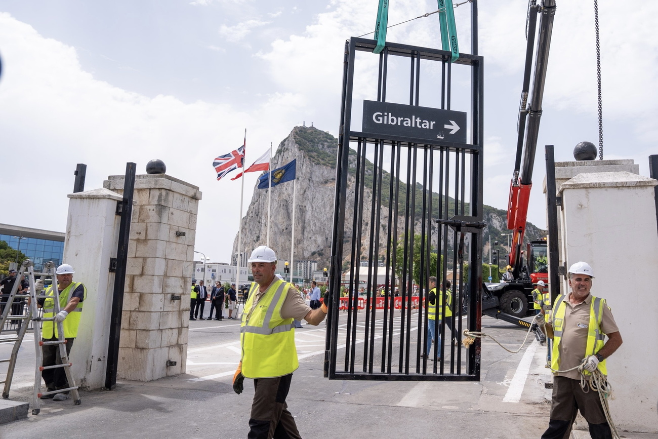 Trabajadores retiran con una grúa una verja de hierro durante un acto simbólico de desmantelamiento de la frontera entre España y Gibraltar.