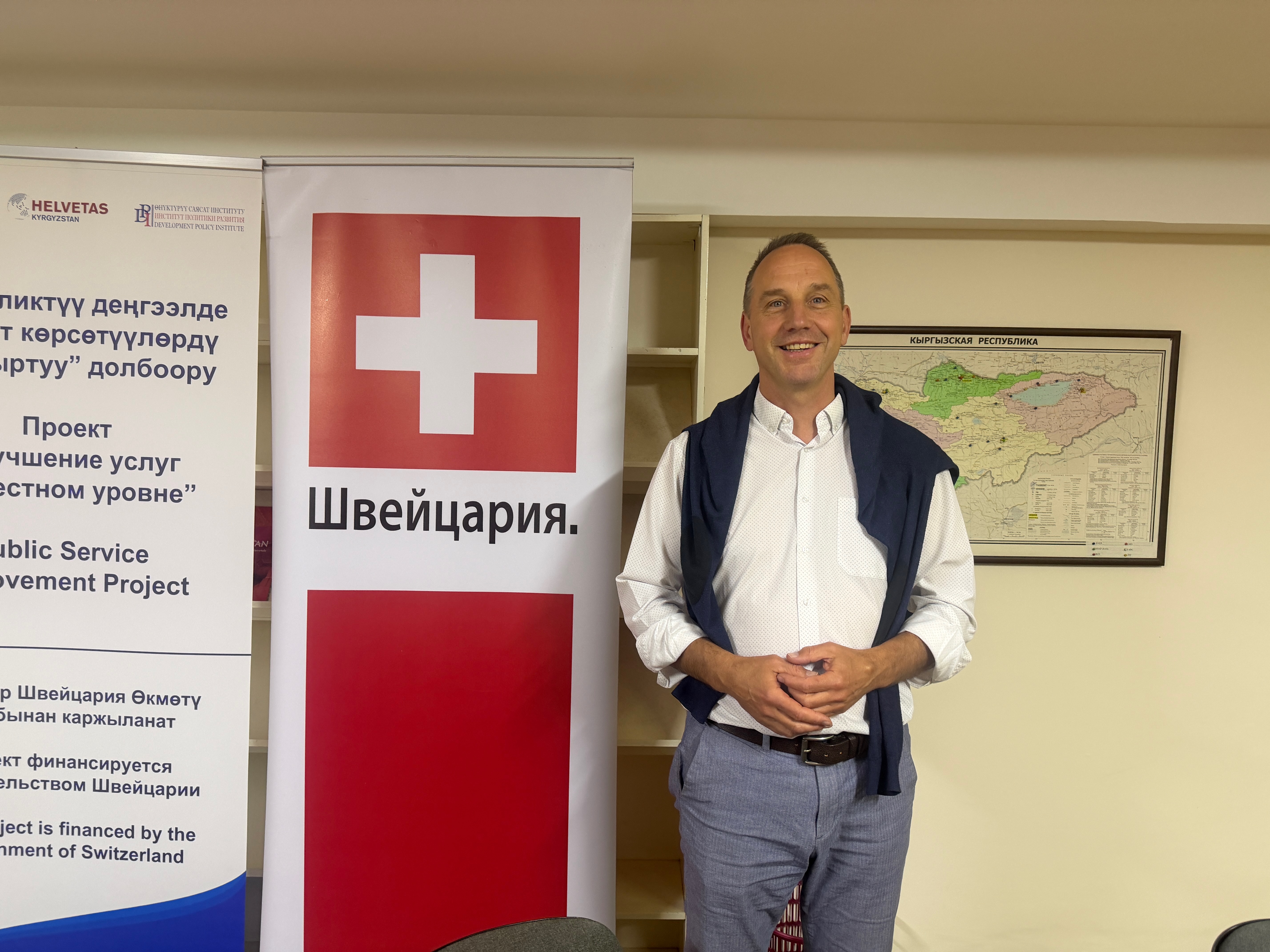 Un homme à côté d'un drapeau suisse dans un bureau
