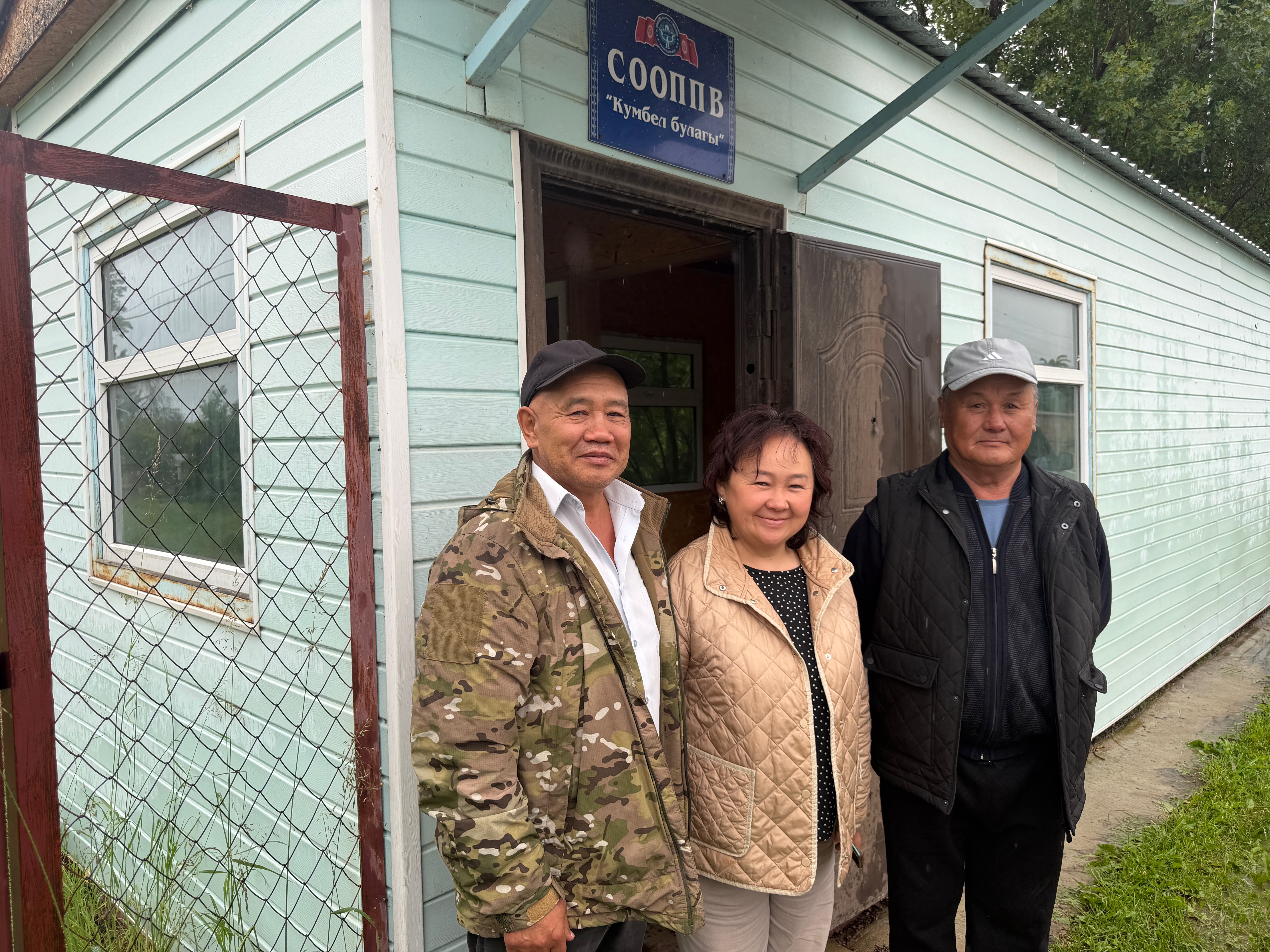 trois personnes près d'une maison en bois blanche