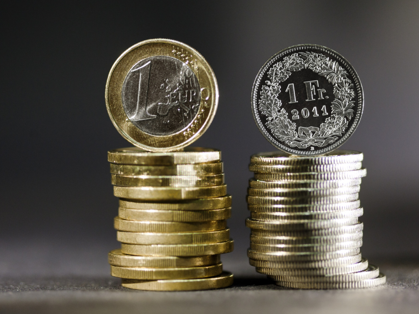 pila di monete da un euro accanto a pila di monete da un franco