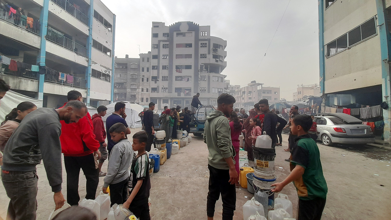 La gente hace cola para recoger agua en Khan Younis, al sur de Gaza. Dada la grave escasez de agua, las familias suelen pasar horas esperando su turno para llenar bidones con agua para sus necesidades diarias.
