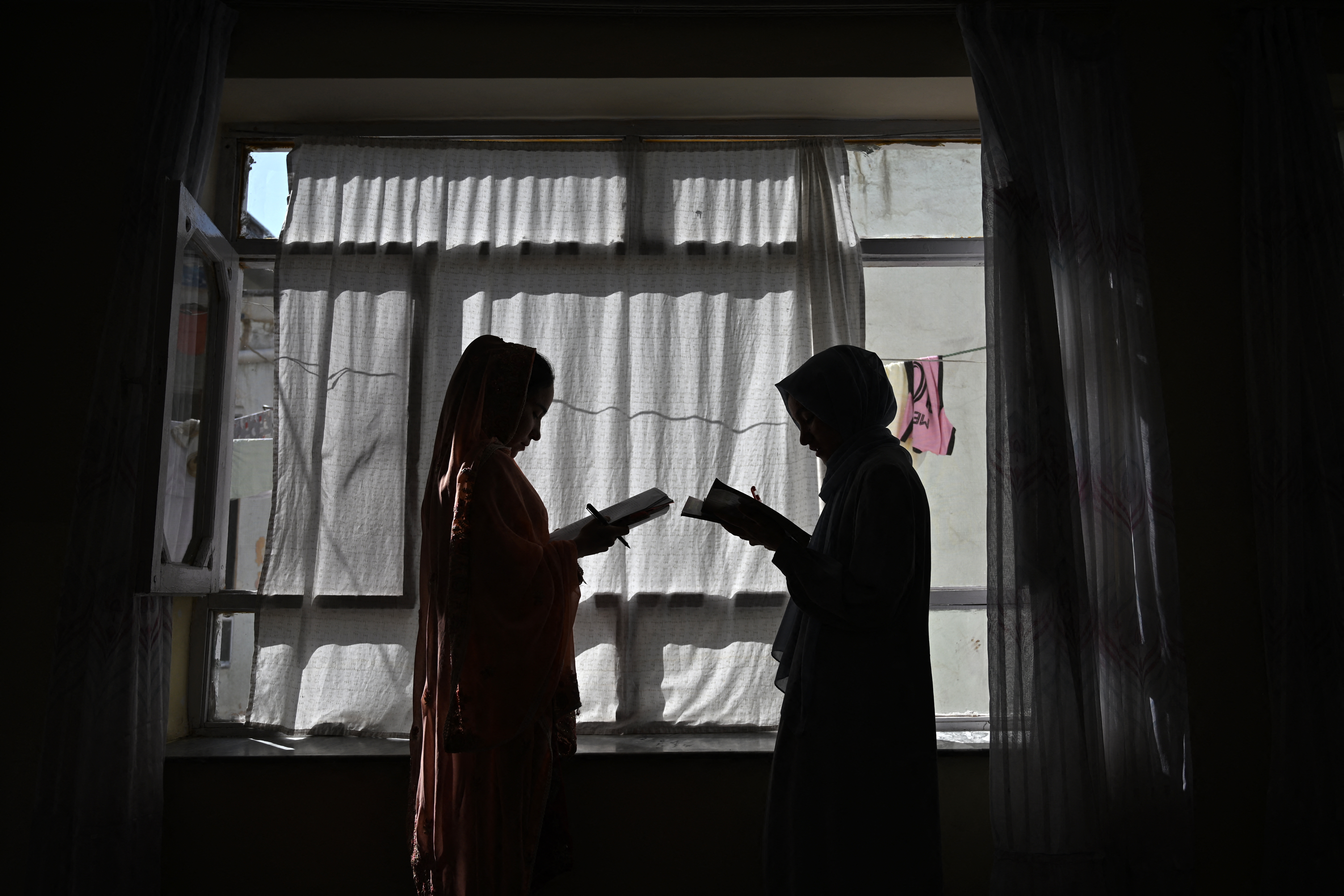 This photograph taken on August 6, 2026 shows Afghan girls attending a lesson given by their father at their residence in Kabul. Father after father AFP spoke to in Afghanistan about the education ban that stops their daughters going beyond primary school choked up in despair. The pain and anguish it is causing behind closed doors is clear from interviews AFP conducted across the country, with even deeply religious fathers questioning the ruling. (Photo by AFP)