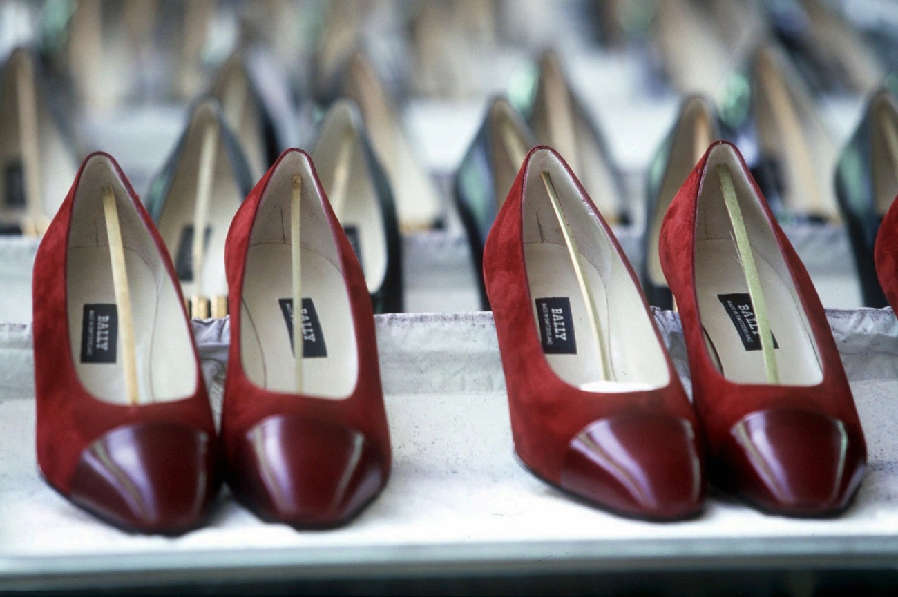 Several pairs of red women's shoes lined up on a display shelf