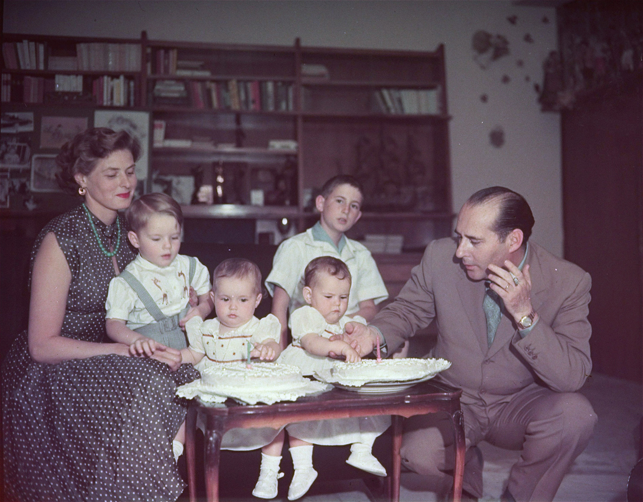Italian film director Roberto Rossellini and his wife, actress Ingrid Bergman, gather around their twins, Isotta and Ingrid, who are looking at their first birthday cakes during a family celebration in Rome, Italy, on June 18, 1953. The actress holds their first child Robertino, while in center background is Renzo Rossellini, the film director's son by a previous marriage.