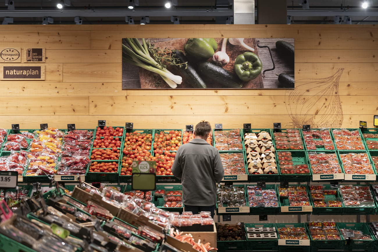 Espositore di ortaggi biologici in un supermercato; una persona sta facendo la spesa
