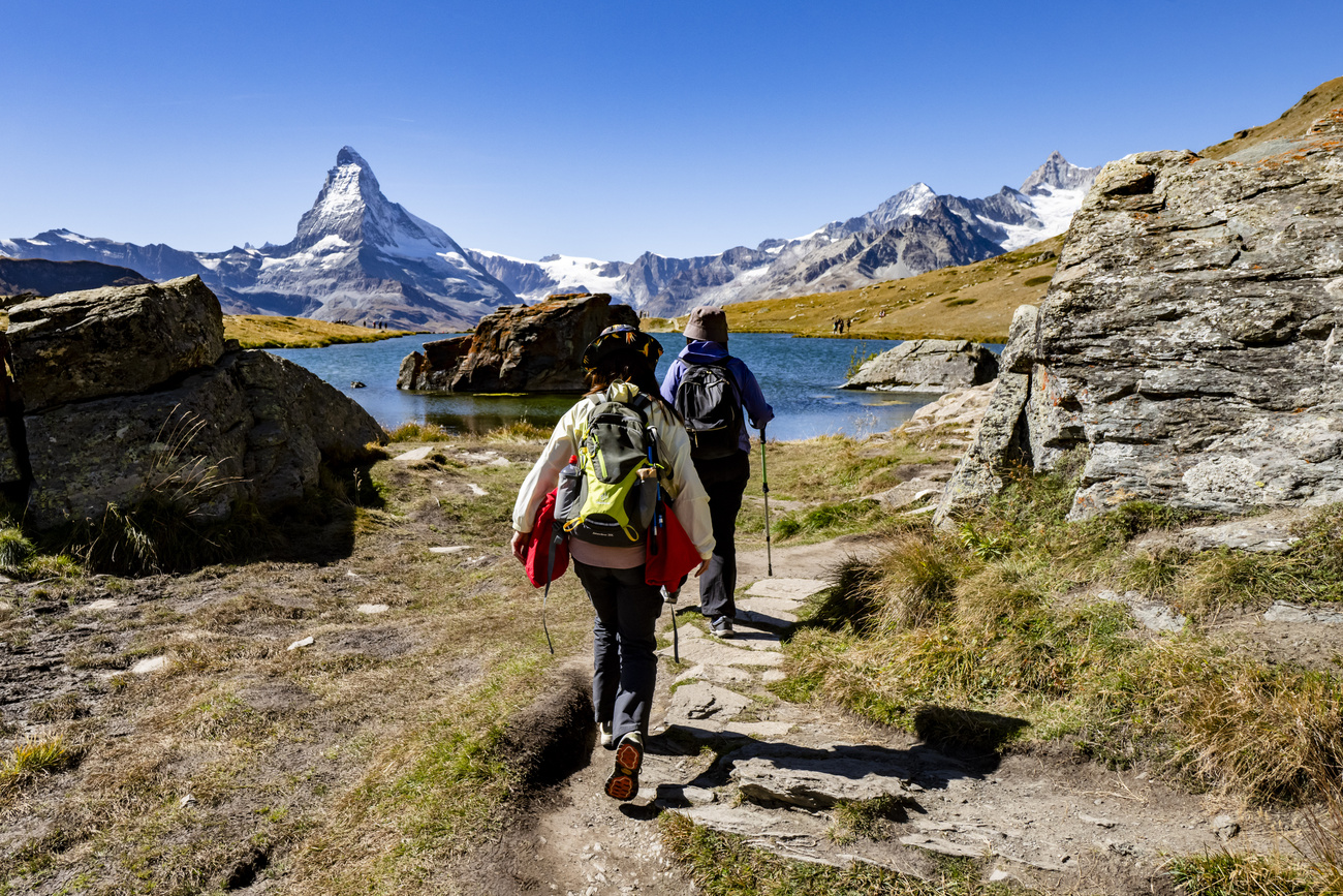 Wandernde in Richtung eines Sees vor einem Berg (Matterhorn)