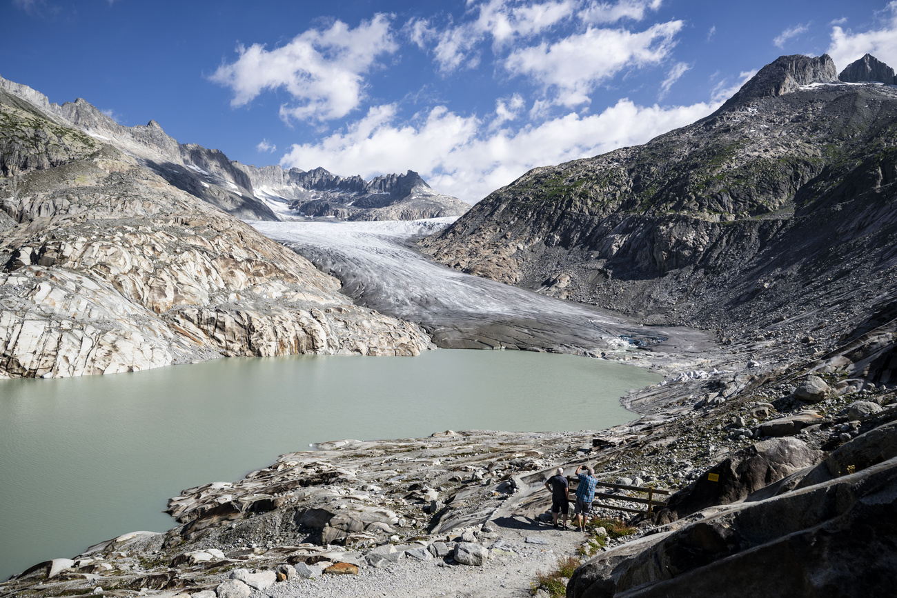 Tourists watch the ice melt in front of the tongue of the Rhone Glacier in southern Switzerland on July 16, 2026.