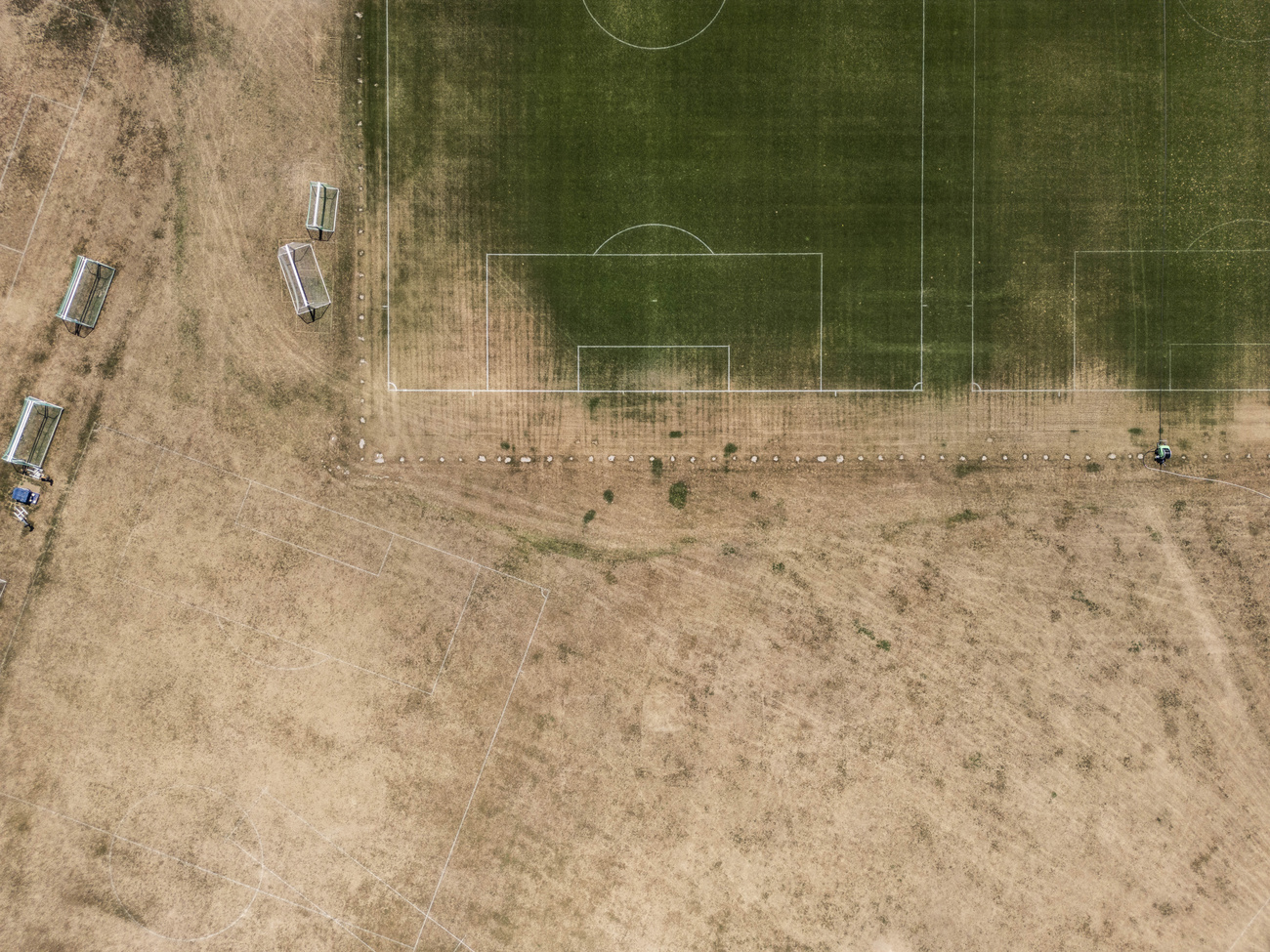 Luftaufnahme von vergilbten Wiesen neben einem Fussballplatz