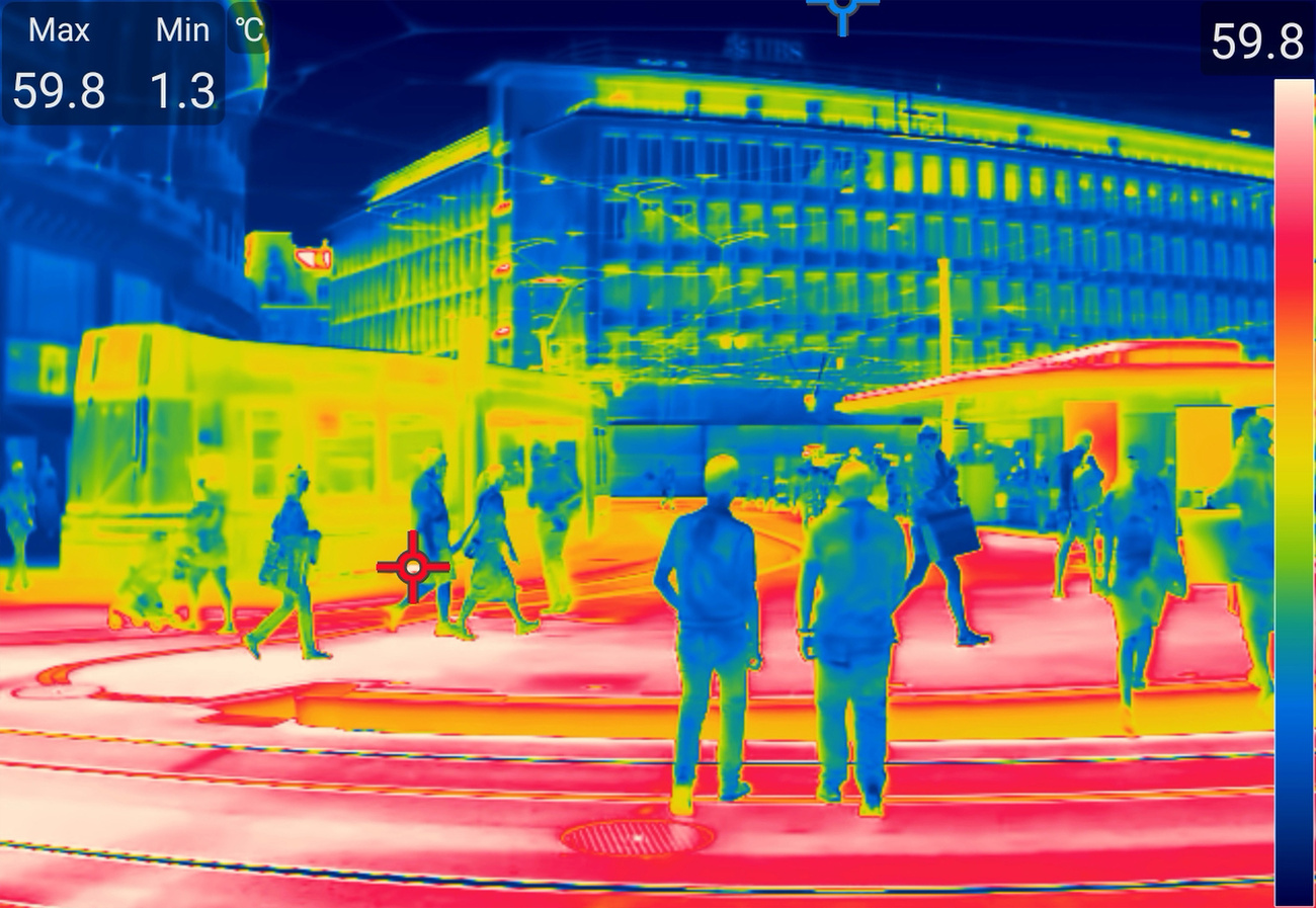 People are photographed walking or standing in the sun on Paradeplatz during the heatwave and extreme temperatures with a thermal imaging camera at approximately 13:55 on Thursday, 30 July 2026, in Zurich. This thermal imaging camera (thermographic camera) captures no visible light and no colours, but rather infrared radiation (heat radiation) emitted from surfaces: blue indicates cold, red indicates hot and white marks the highest temperatures.