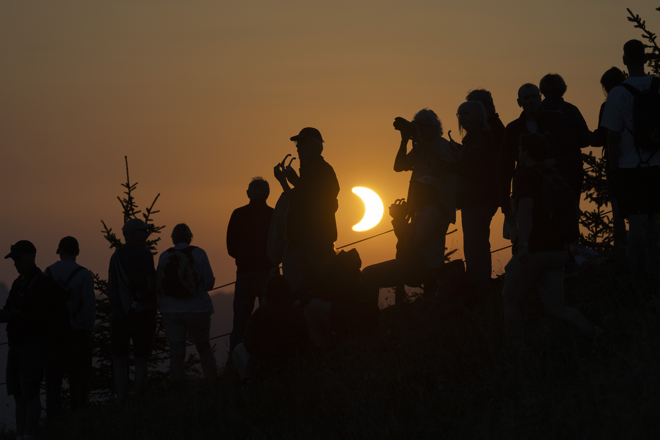 Persone in controluce, eclissi solare sullo sfondo